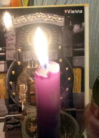 Brennende Kerze vor Accessories und Postkarte aus Wien